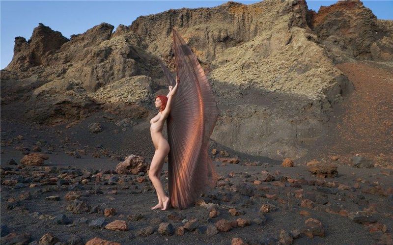 young red haired girl with butterfly wings on rocky mountains