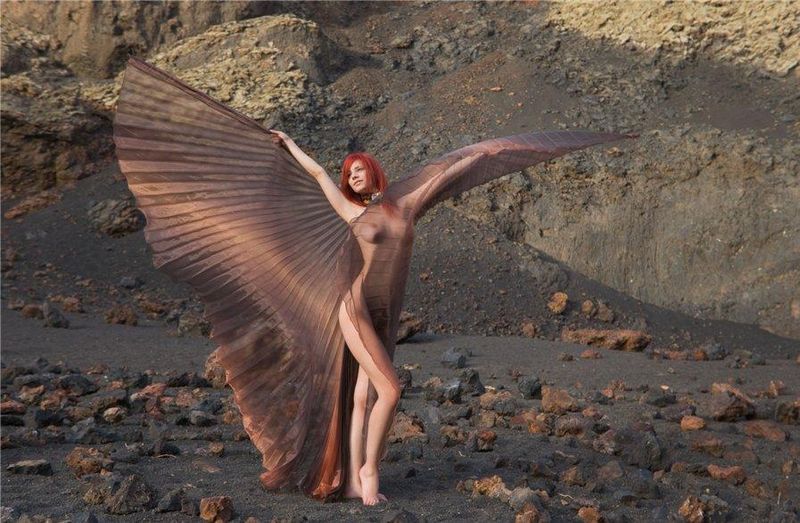 young red haired girl with butterfly wings on rocky mountains