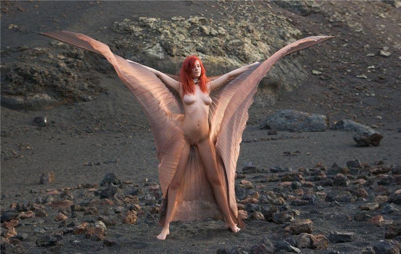 young red haired girl with butterfly wings on rocky mountains