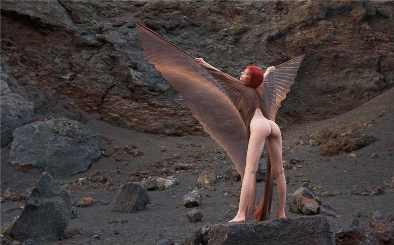 young red haired girl with butterfly wings on rocky mountains