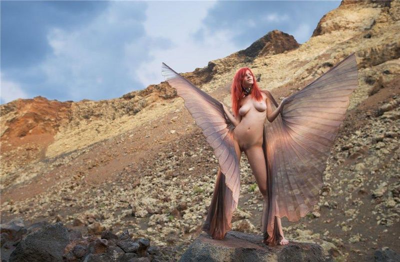 young red haired girl with butterfly wings on rocky mountains