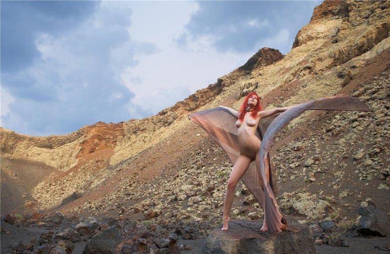 young red haired girl with butterfly wings on rocky mountains