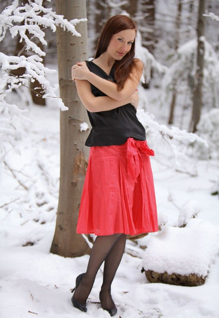 young red haired girl strips to black stockings in the winter forest