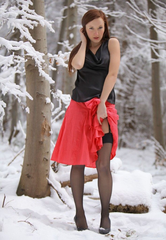 young red haired girl strips to black stockings in the winter forest