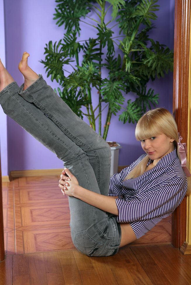 young blonde girl strips her jeans at home between the door