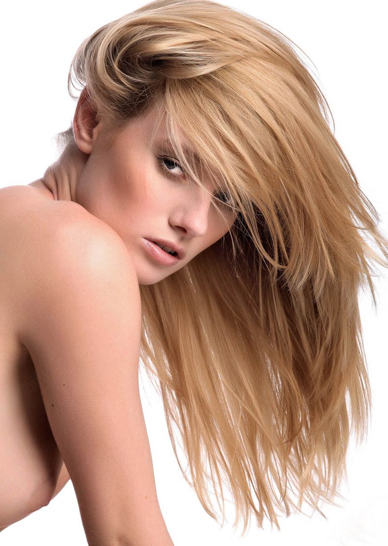 young blonde girl undresses her black lingerie and posing with small stones in the studio