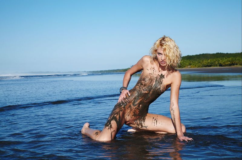 young curly blonde girl on the beach dirty from sand