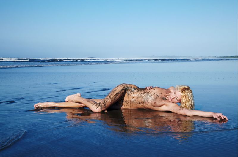 young curly blonde girl on the beach dirty from sand