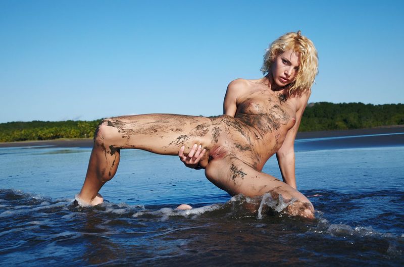 young curly blonde girl on the beach dirty from sand