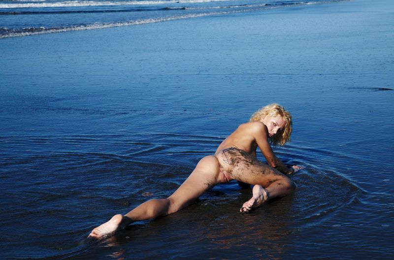 young curly blonde girl on the beach dirty from sand