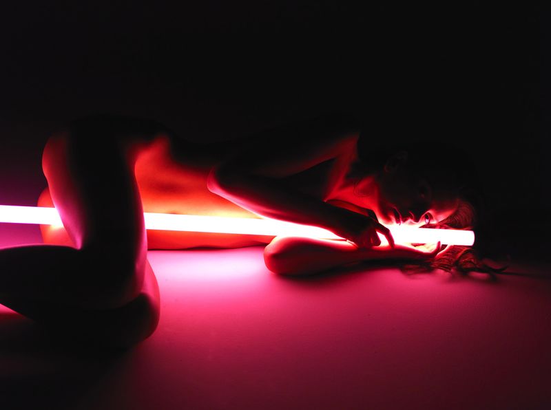 cute young brunette girl posing with a neon tube lamp