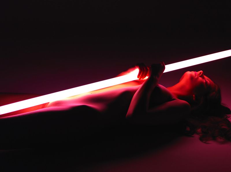 cute young brunette girl posing with a neon tube lamp