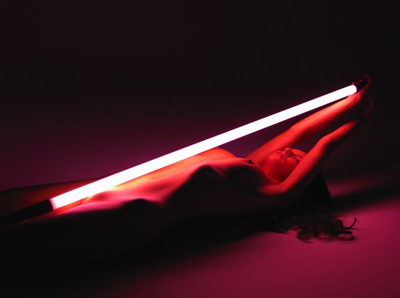 cute young brunette girl posing with a neon tube lamp