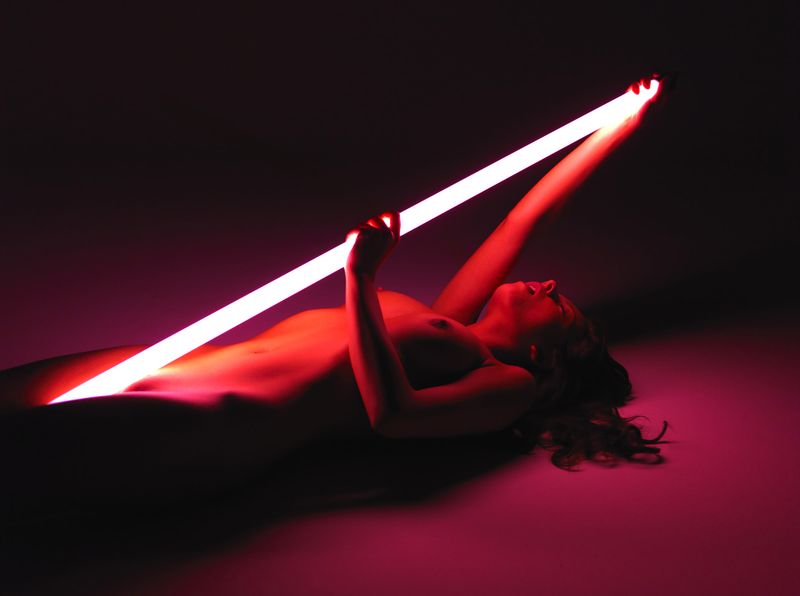 cute young brunette girl posing with a neon tube lamp