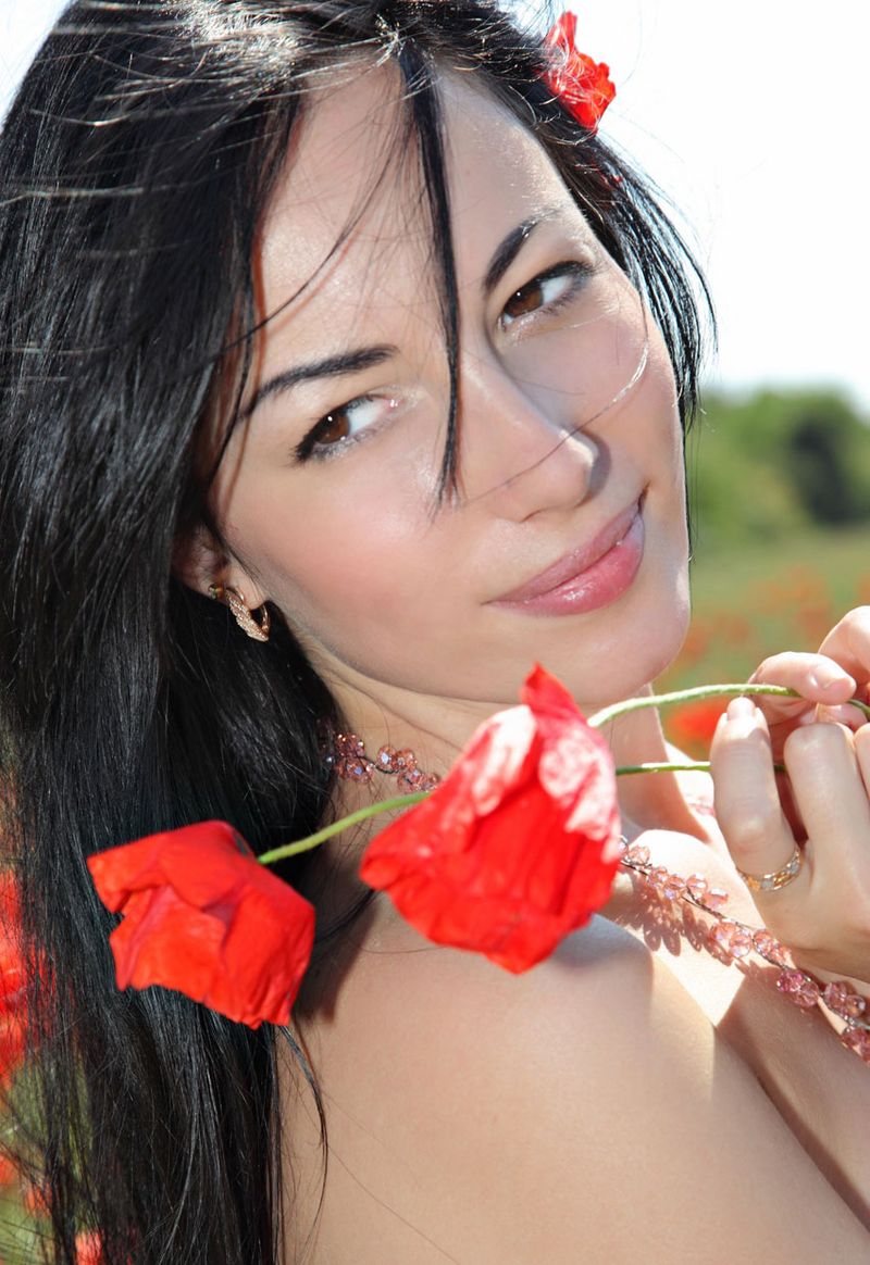 young black haired girl outside on the field with red poppies