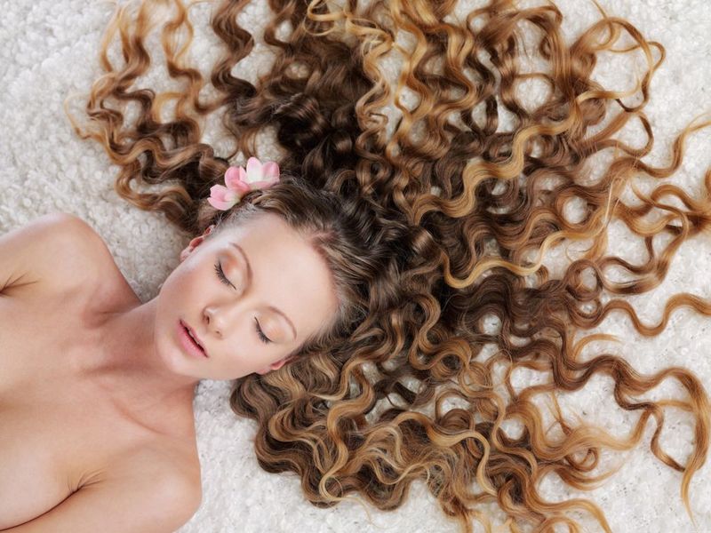 young curly blonde girl reveals on the wooden swing seat