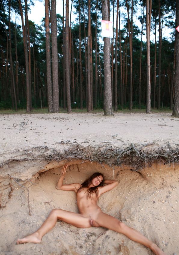 young brunette girl with large labia minora in the sand near the forest