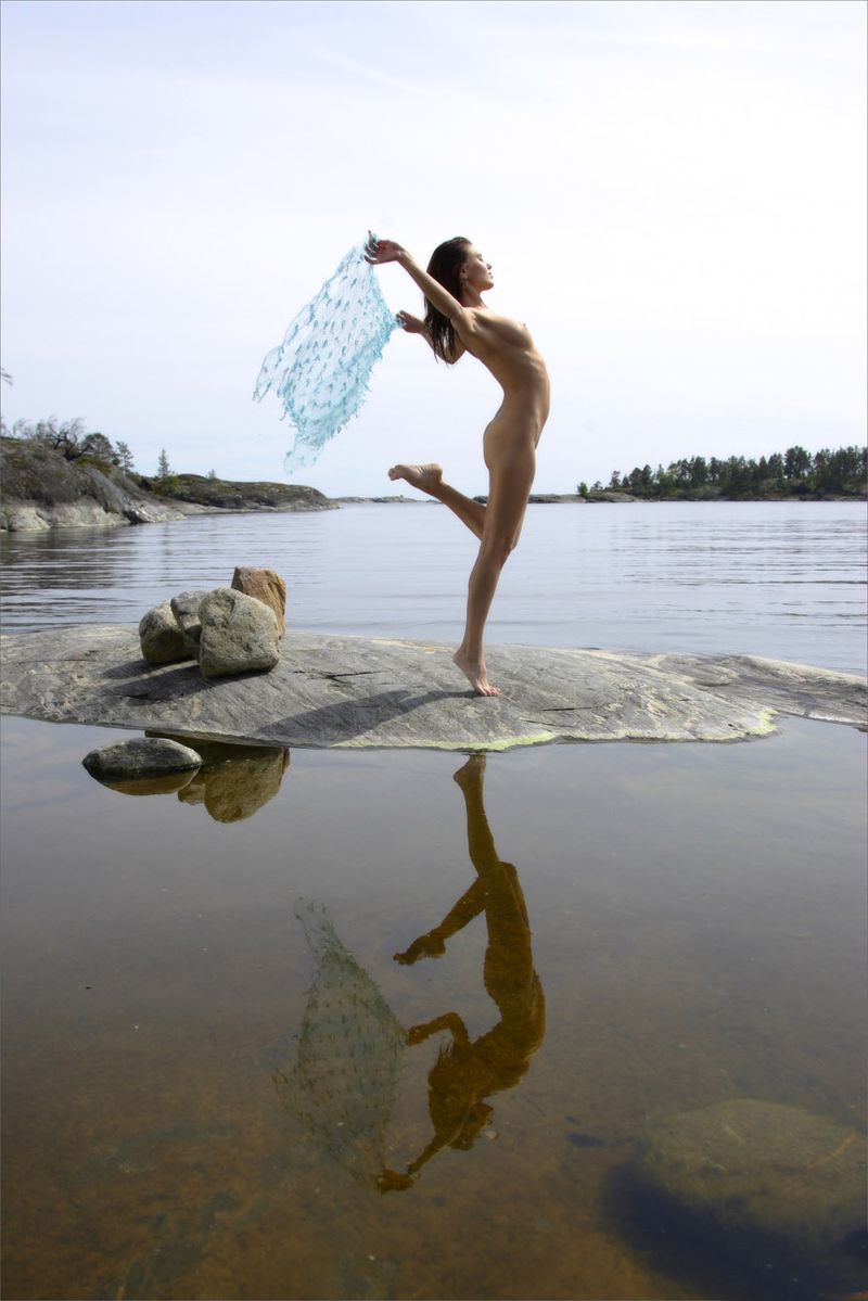 young brunette girl at the lake on rocks with a blue scarf