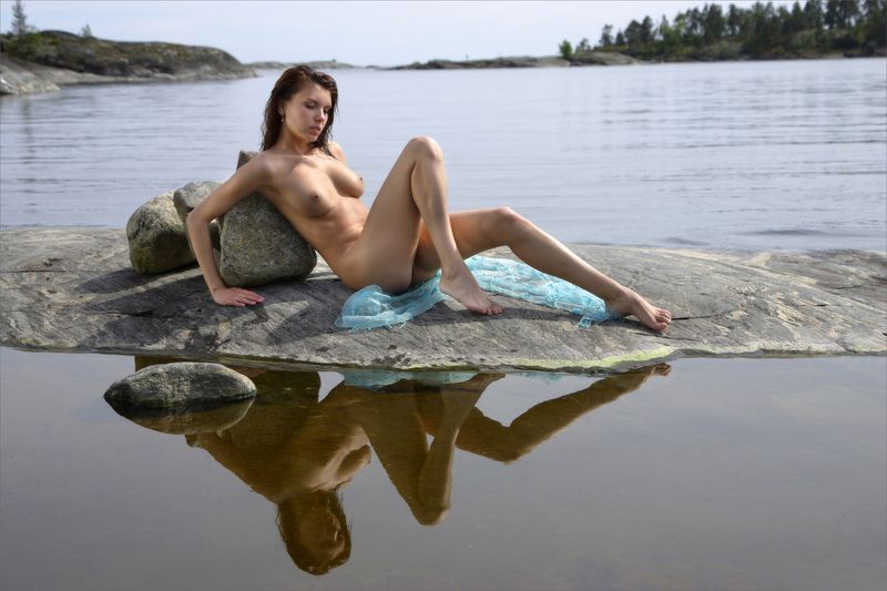 young brunette girl at the lake on rocks with a blue scarf