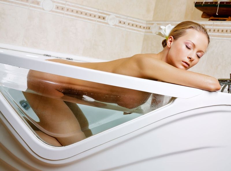 young blonde girl with long hair reveals in the bathtub with a small ship