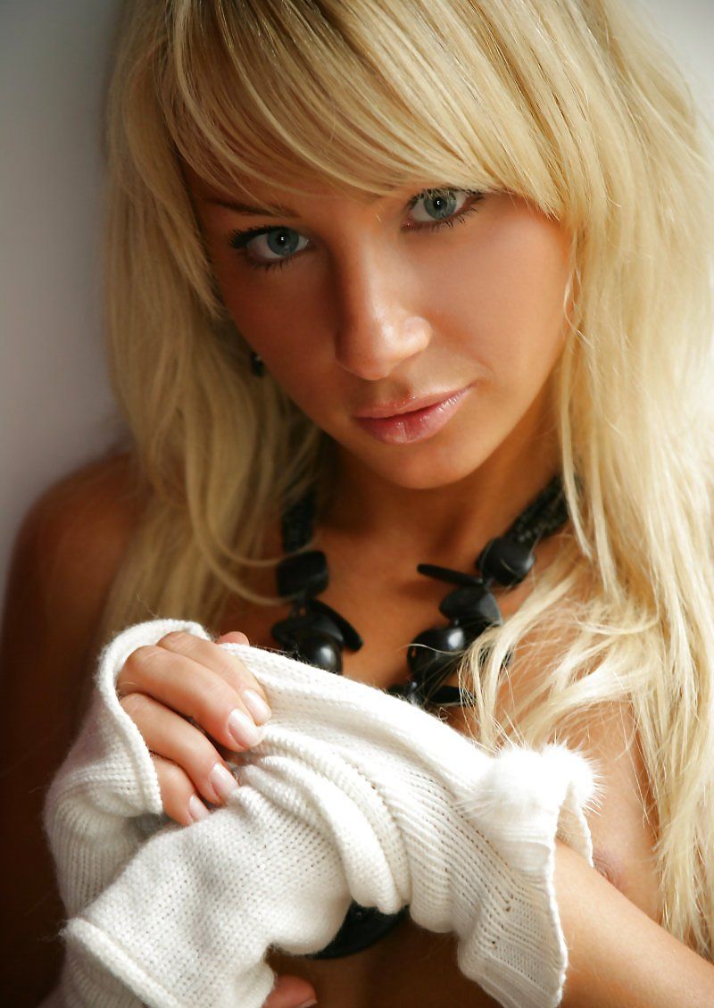 cute young blonde girl with a black necklace posing at the window