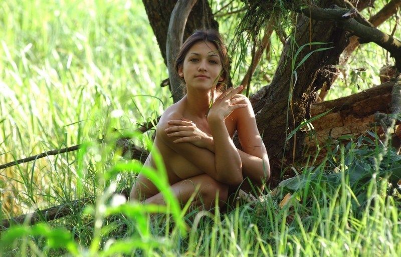 cute young brunette girl with full breasts in the swamp at the big tree