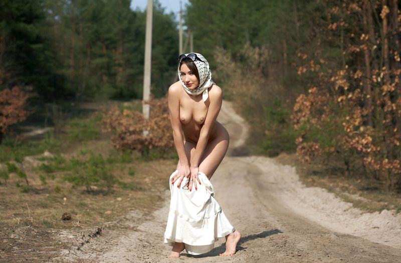brunette girl with a white skirt, headscarf and sunglasses reveals on the rural forest road