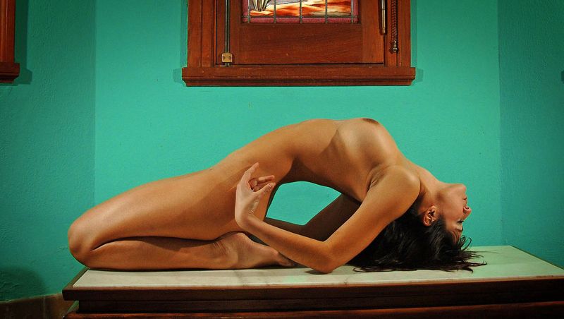 brunette girl doing gymnastic exercises in the church with stained glass windows