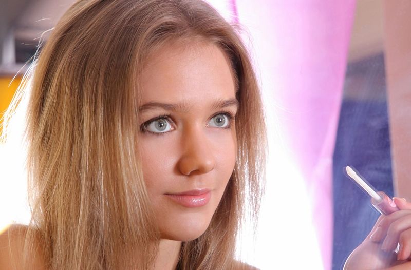 cute young dark blonde girl with blue eyes reveals in a violet corset at the mirror