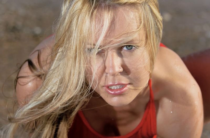 blonde girl reveals her red chemise on the beach in the sea