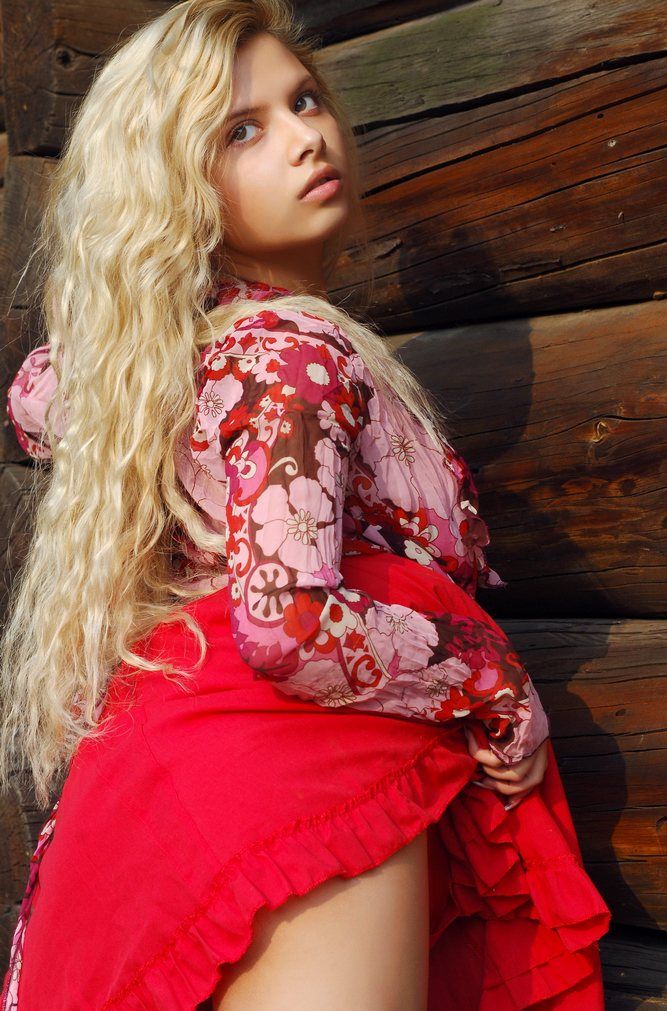 young curly blonde girl wearing a red dress in the village