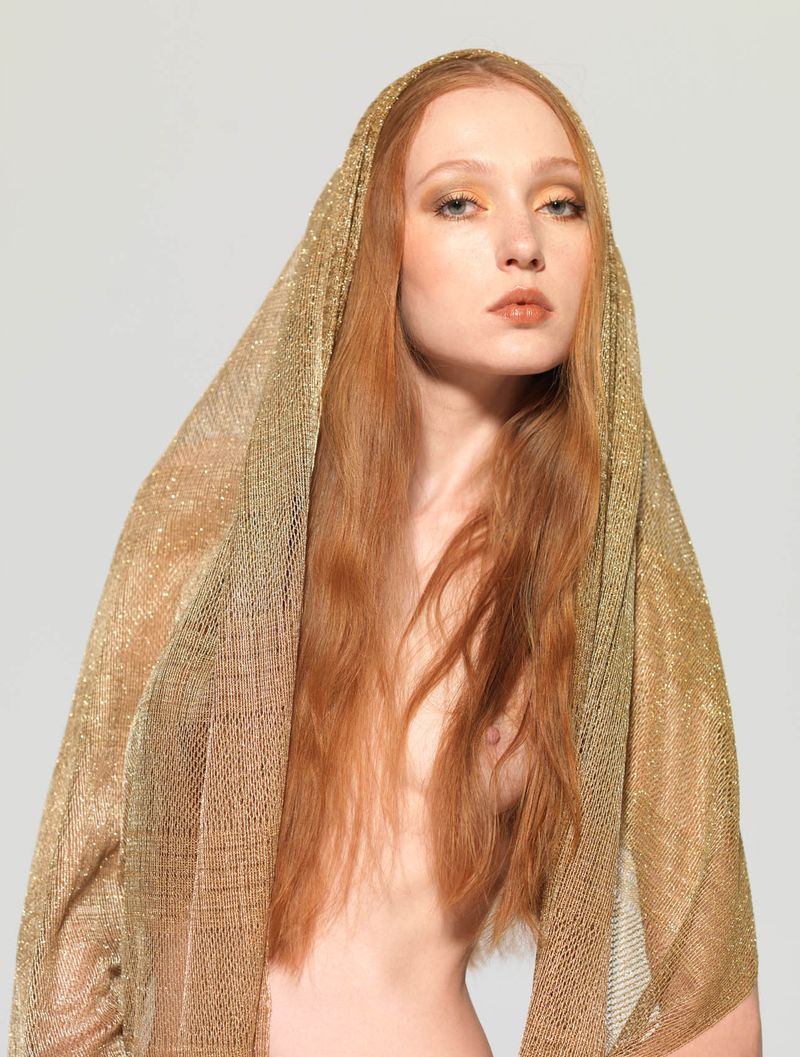 young red haired girl shows off with a golden scarf in the studio