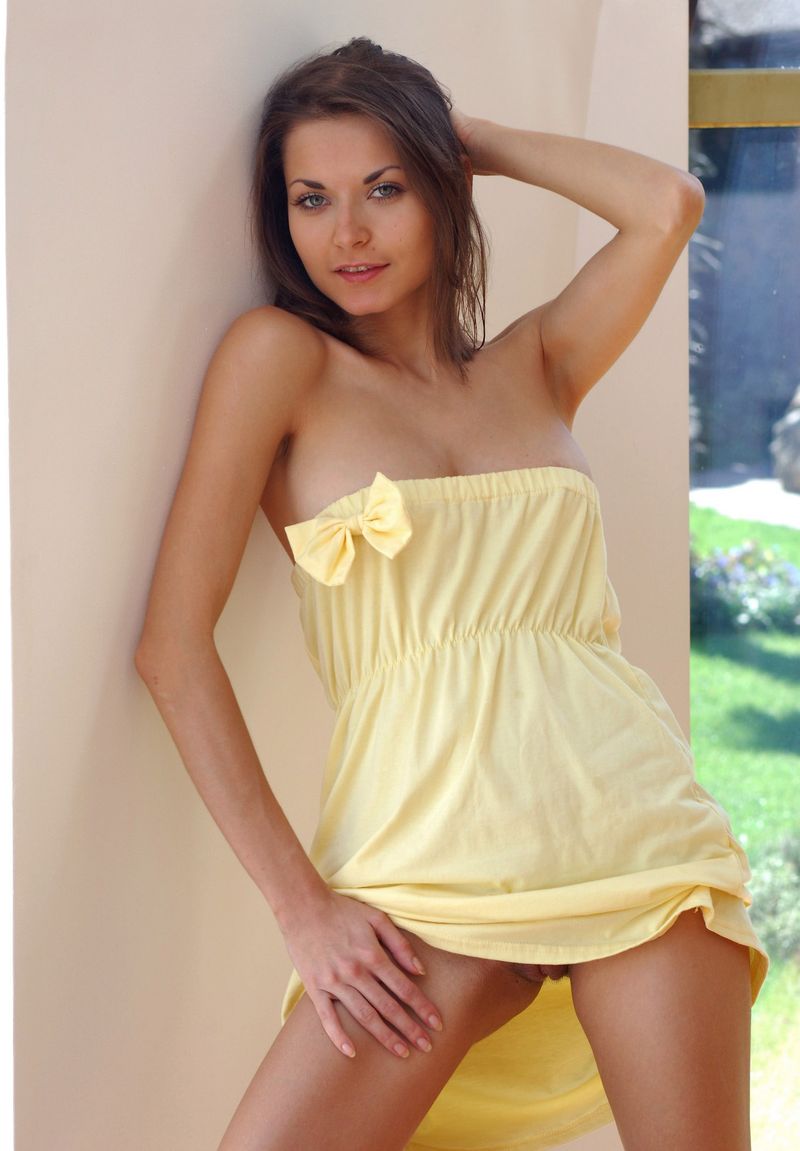 young brunette girl reveals her yellow dress near the window at home