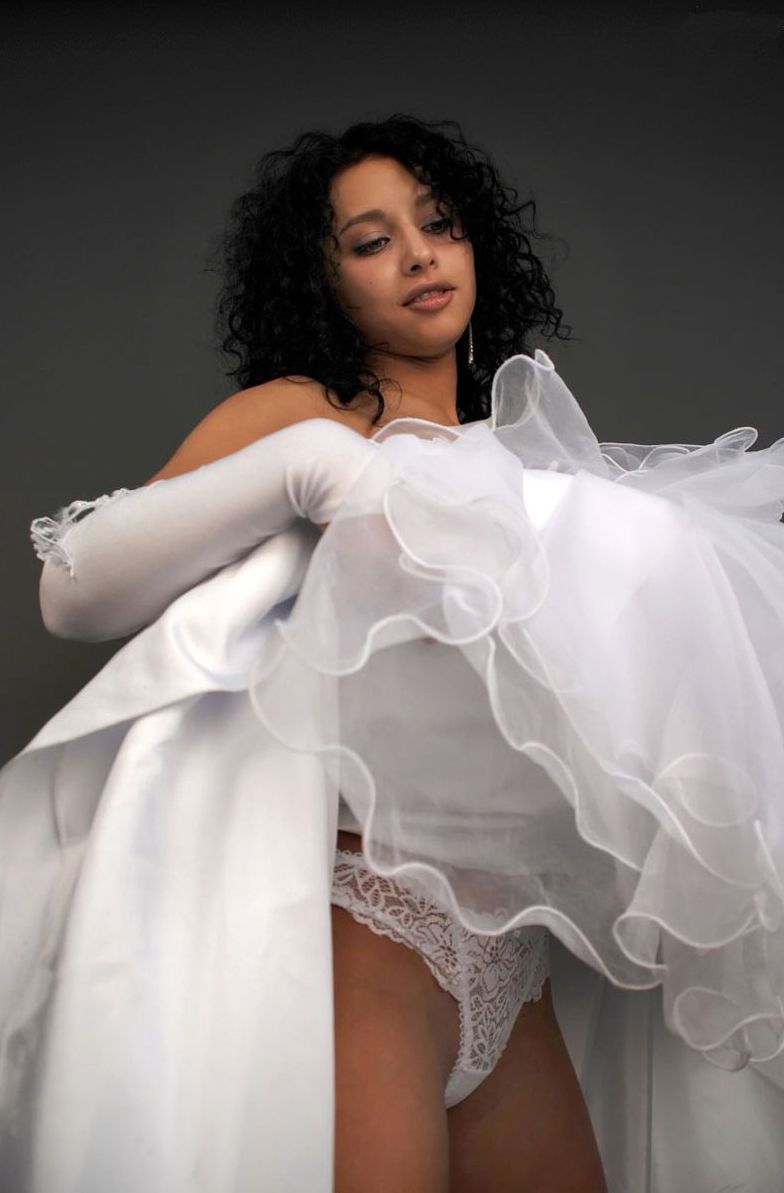 curly black haired girl strips her wedding dress in the studio