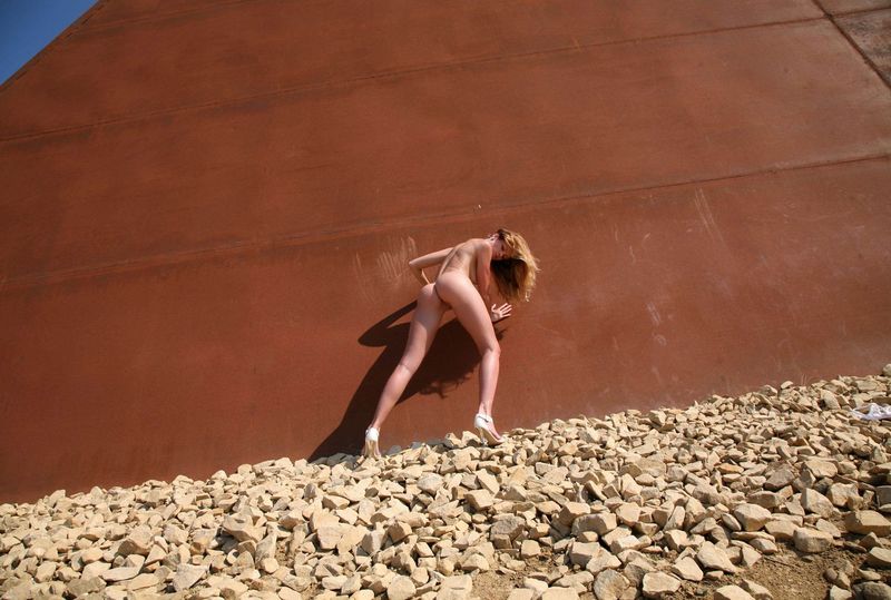 young blonde girl undresses a white lingerie on the rocky hill with obelisk