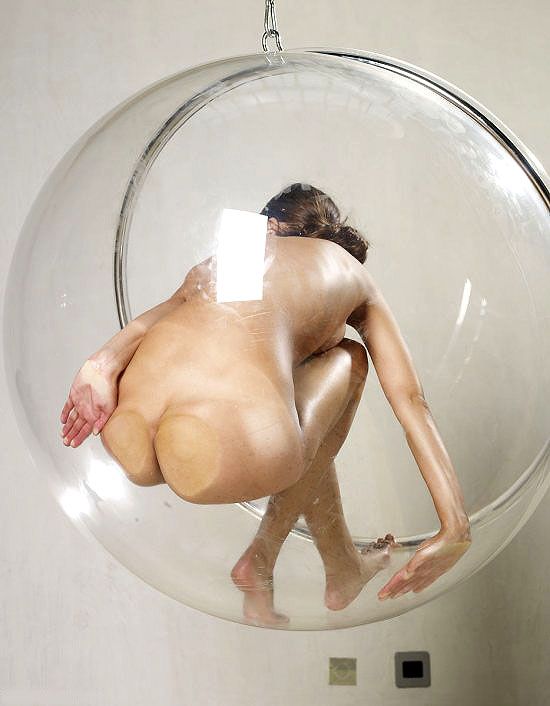 young brunette girl posing in a transparent vitreous glass swing chair