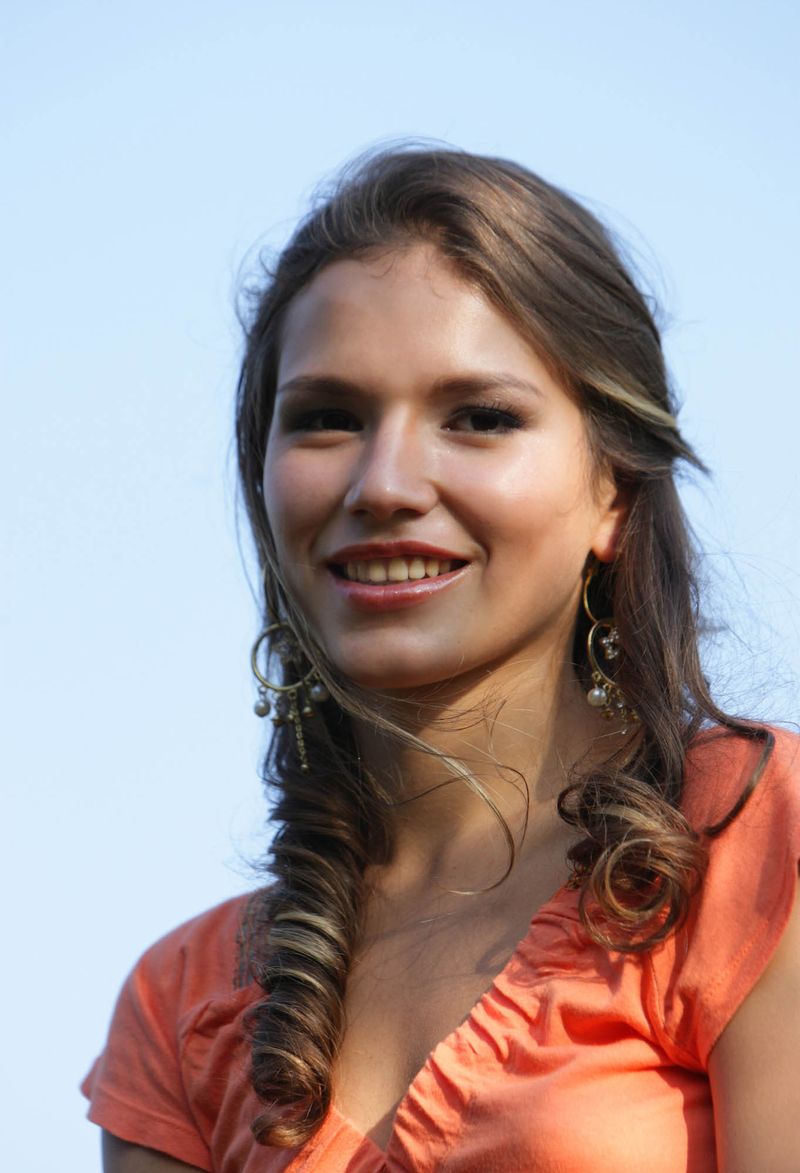 young curly brunette girl with high heels reveals her orange top on the bridge at the railway track