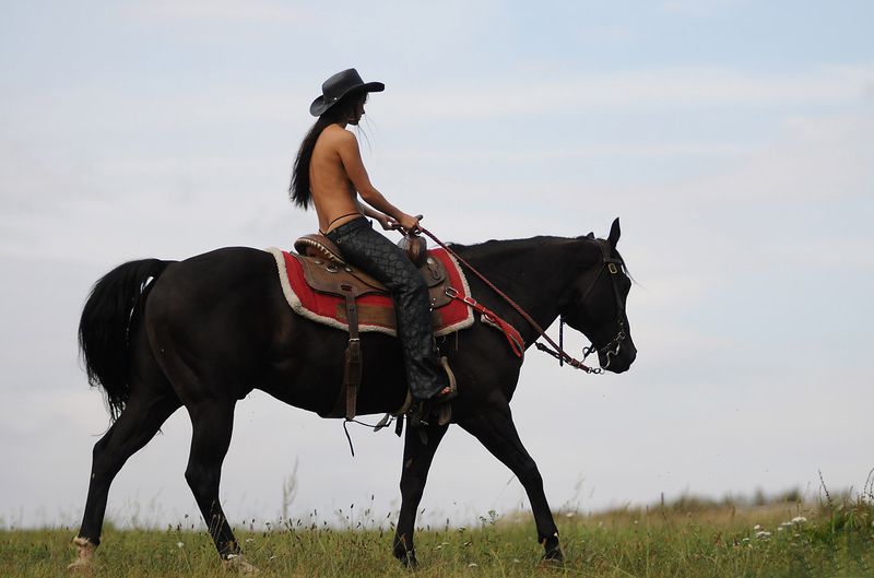 brunette girl shows off her cowboy skills with a horse and colt revolver