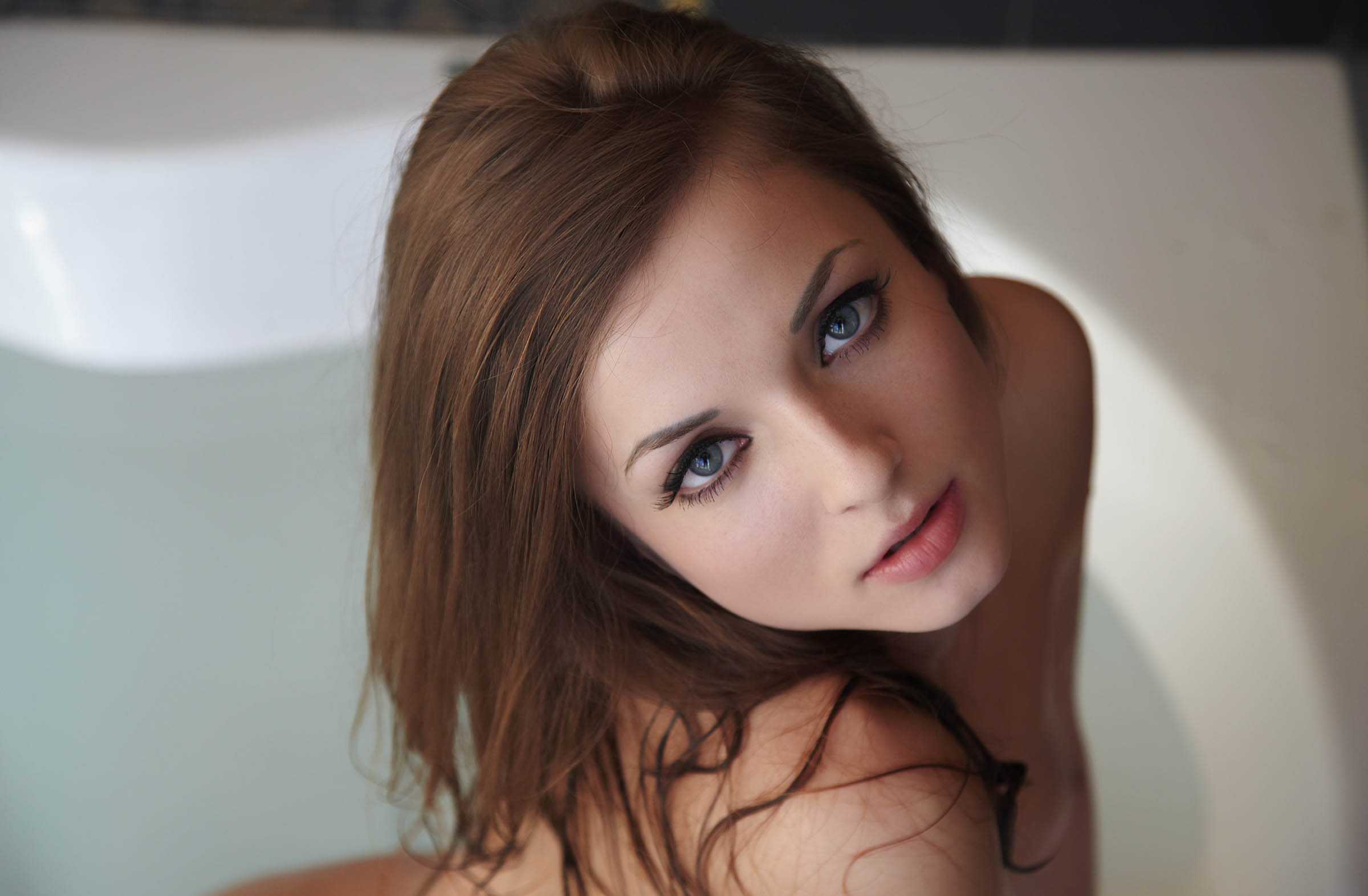 young brunette girl with blue eyes shows off in the bathtub