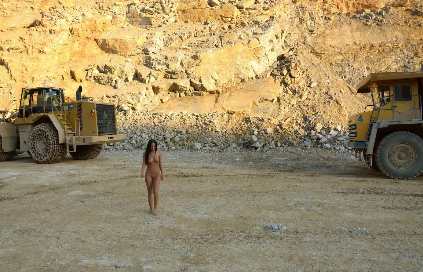 young black haired girl posing with heavy construction equipment vehicles of various types