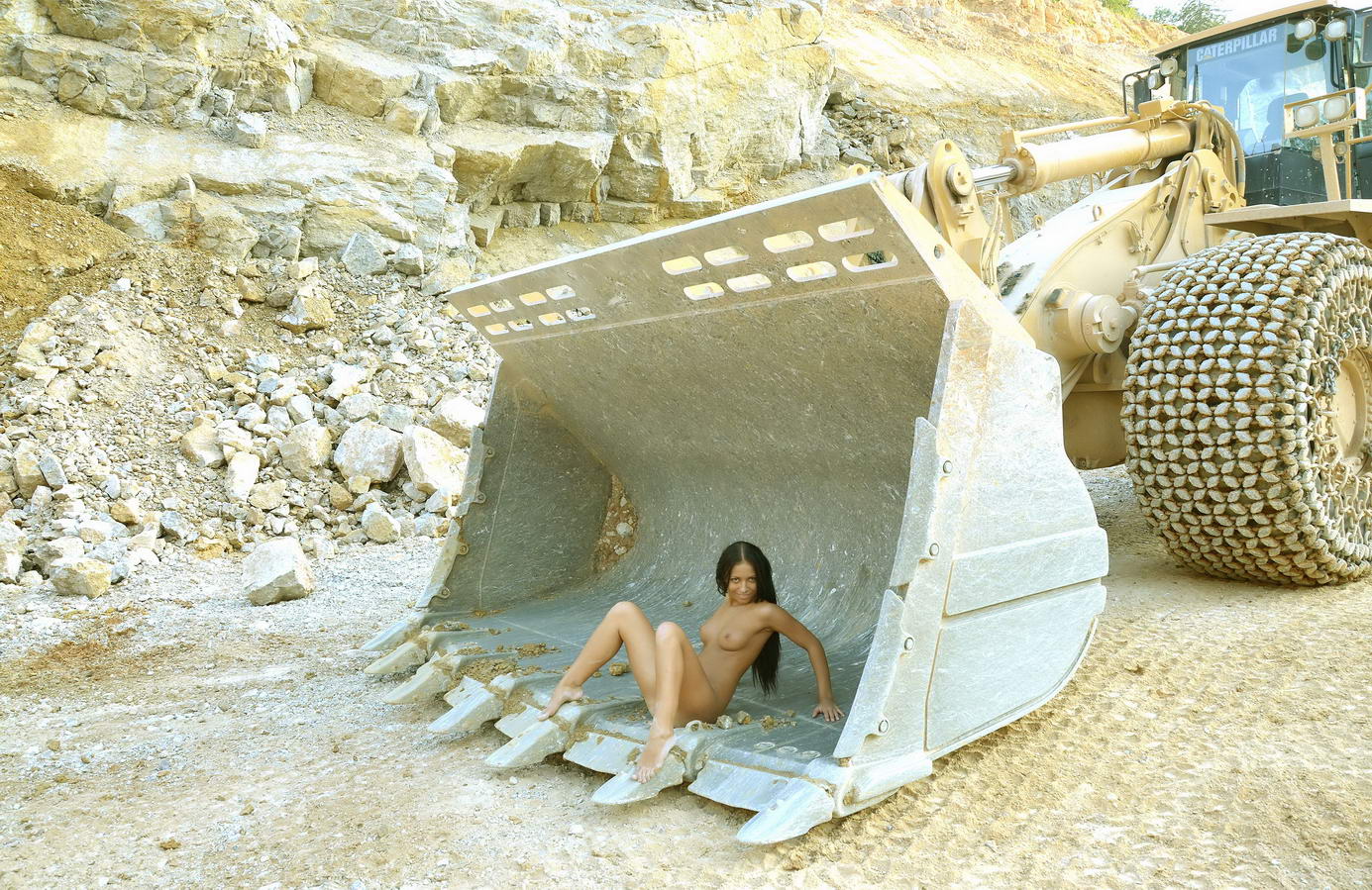 young black haired girl posing with heavy construction equipment vehicles of various types