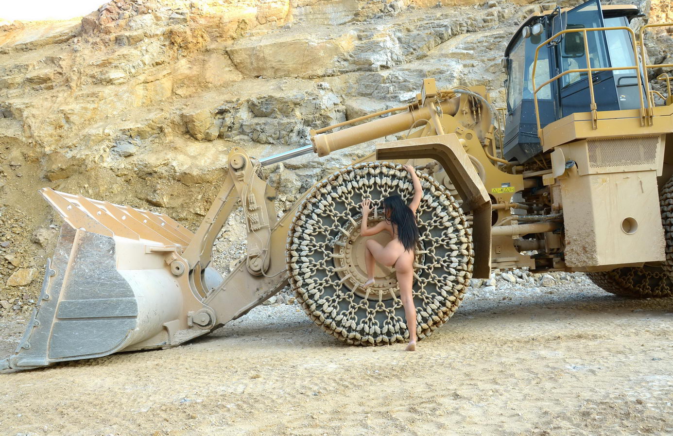 young black haired girl posing with heavy construction equipment vehicles of various types
