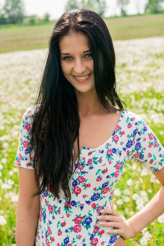 young black haired girl undresses her bodysuit on the field of dandelions