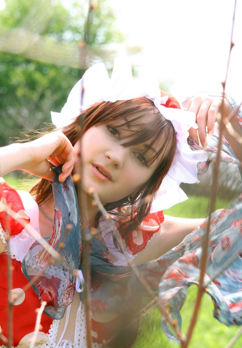 young red haired girl reveals her red and white dress with white panties outside on the grassy glade meadow