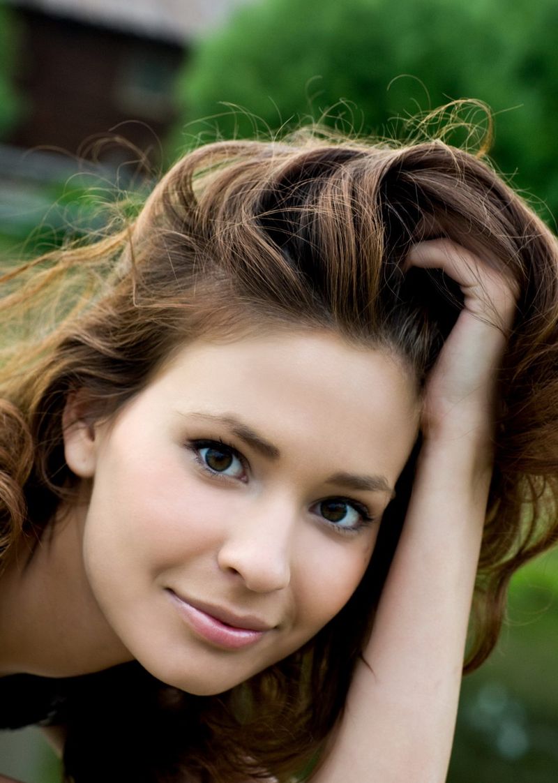 cute young brunette girl reveals her black and white dress in the countryside with a village house