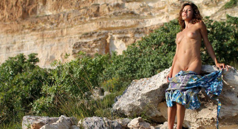 young curly brunette girl reveals her dress outside on rocky mountains