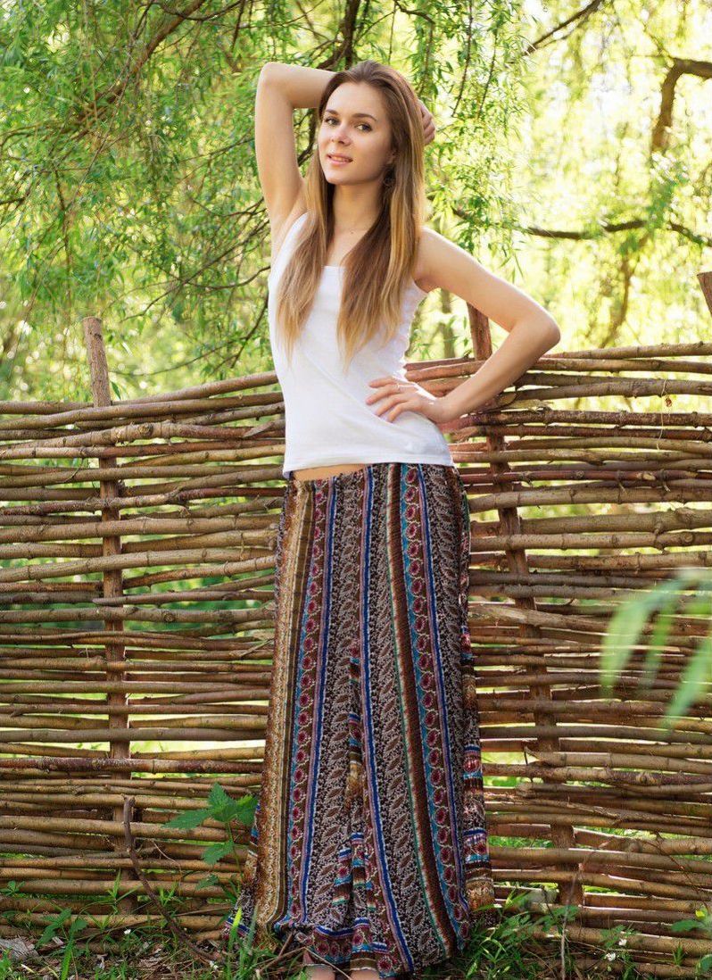 young dark blonde girl reveals her dress near the wooden fence