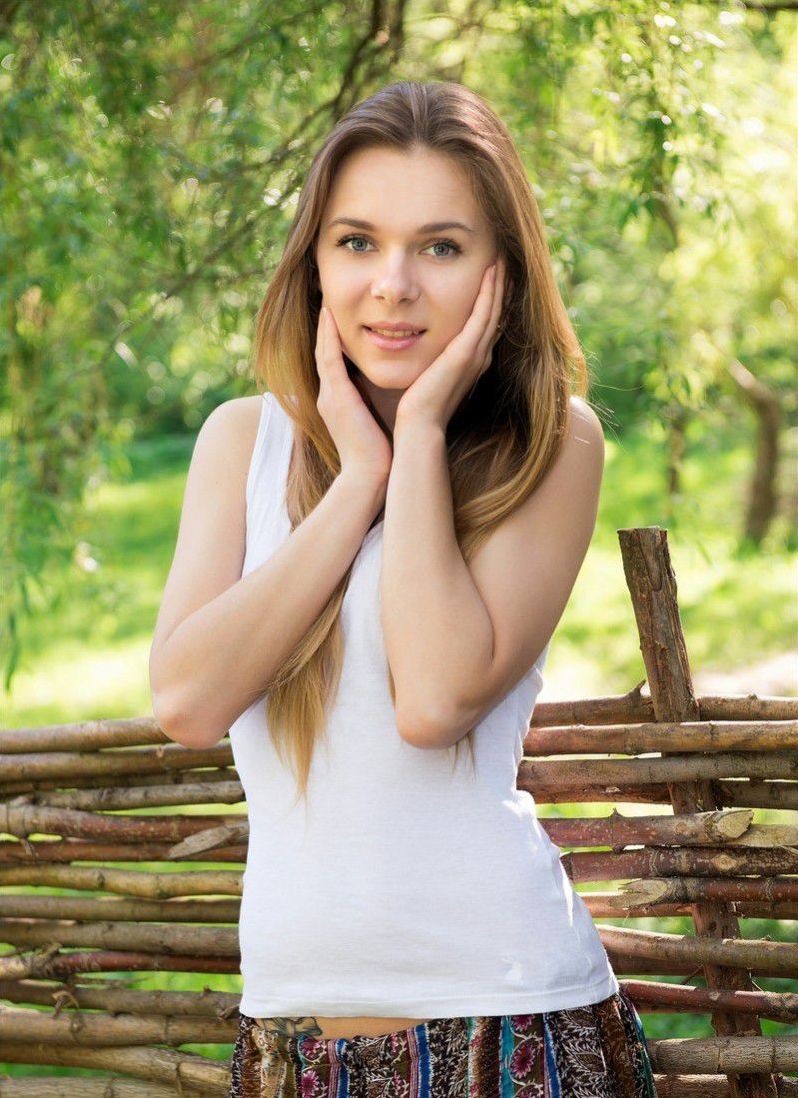 young dark blonde girl reveals her dress near the wooden fence