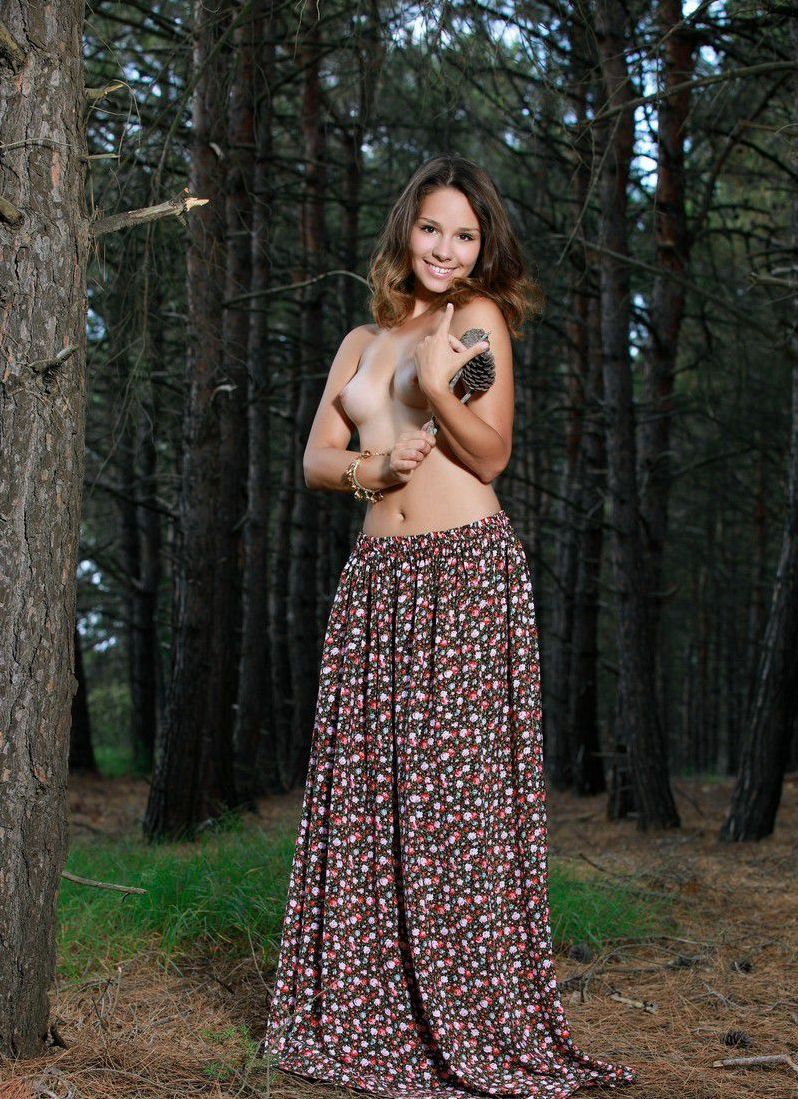 young brunette girl with a bracelet reveals her dress in the dark forest