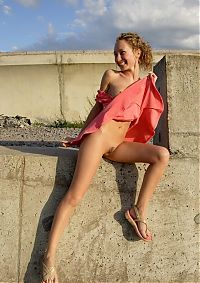 Babes: young curly blonde girl in pink dress near concrete walls